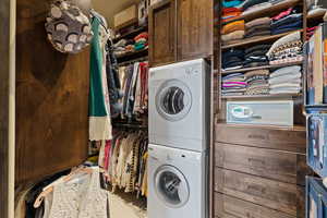 Primary closet with Laundry area featuring stacked washer / dryer and cabinet space