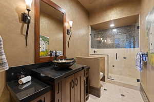 3/4 Powder Bathroom with a textured wall, vanity, a stall shower, and light tile patterned floors