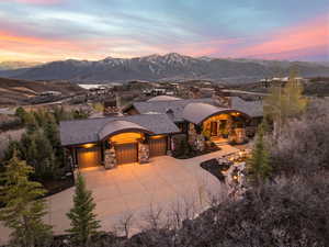 View of front facade featuring stone siding, a mountain view, an attached garage, and driveway