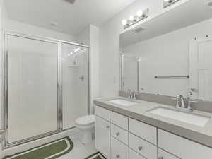 Bathroom with double vanity, a shower stall, and light tile patterned flooring