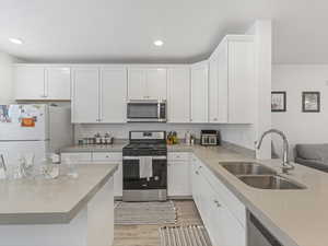 Kitchen with stainless steel appliances, white cabinetry, light wood-style floors, and recessed lighting