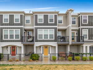 View of front facade with a fenced front yard, stucco siding, and a balcony