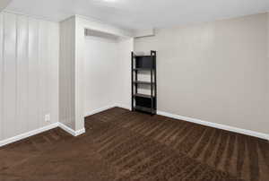Empty room with baseboards and dark carpet