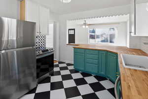 Dual tone kitchen featuring stainless steel appliances, dual tone cabinets, butcher block counters, dark floors, and a peninsula