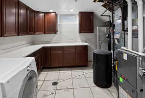 Laundry room with washer / dryer, heating unit, a textured ceiling, light tile patterned flooring, and cabinet space