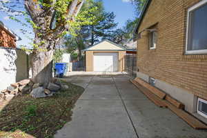 View of property exterior featuring brick siding, a garage, concrete driveway, and an outdoor structure
