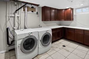 Laundry area featuring washer and dryer, cabinet space, a textured ceiling, and light tile patterned flooring