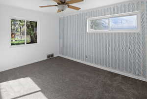 Unfurnished room featuring dark carpet and a ceiling fan