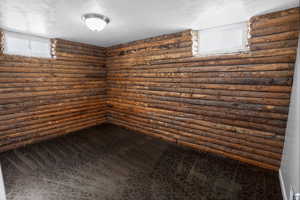 Spare room with rustic walls, dark carpet, and a textured ceiling