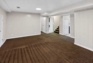 Finished basement featuring stairway and dark carpet