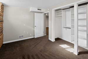 Unfurnished bedroom featuring a closet and dark colored carpet
