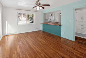 Unfurnished living room featuring a textured ceiling, dark wood-type flooring, and a ceiling fan