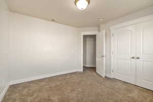 Unfurnished bedroom with light colored carpet and a closet