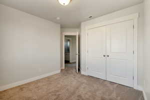 Unfurnished bedroom featuring light carpet and a closet