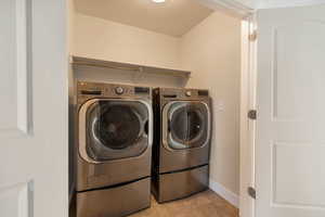 Laundry area with light tile patterned floors and washer and clothes dryer