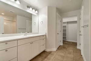 Master bathroom featuring vanity, a spacious closet, light tile patterned floors, and a shower