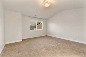 Empty room with light colored carpet and lofted ceiling