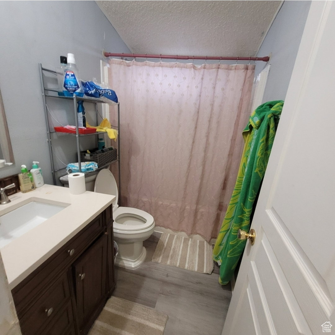 Bathroom with vanity, light wood-type flooring, a textured ceiling, and shower / bath combination with curtain