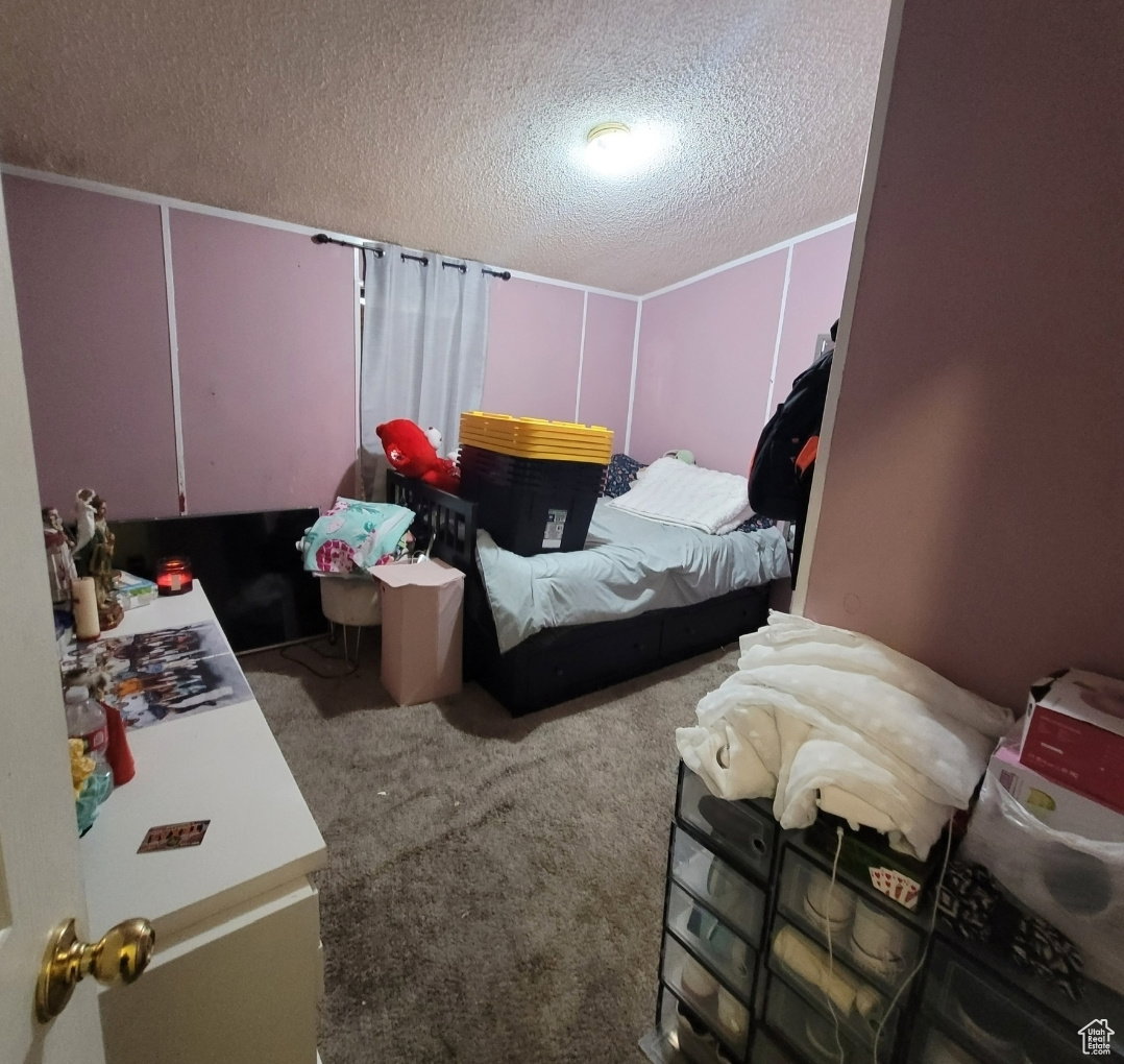 Bedroom featuring a textured ceiling, carpet, and a decorative wall