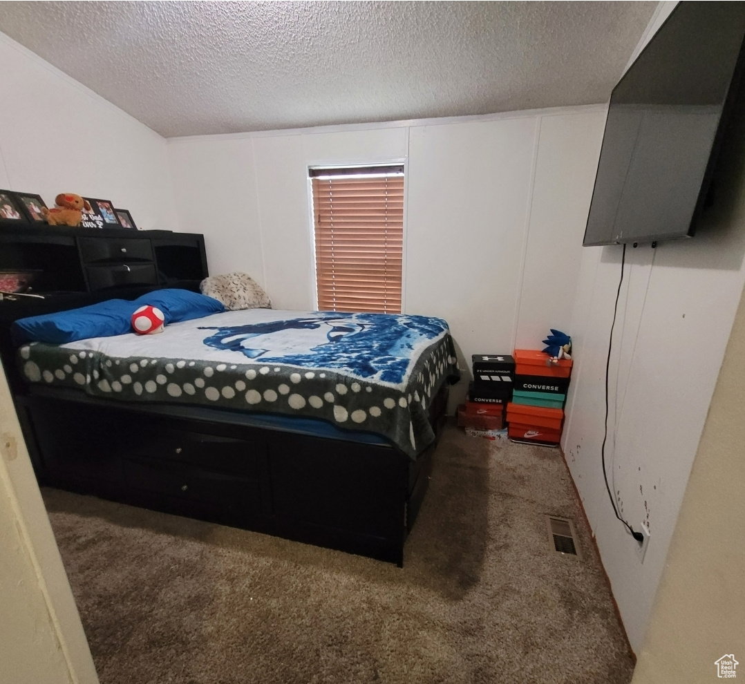 Bedroom featuring a textured ceiling and dark colored carpet
