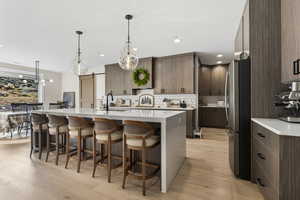 Kitchen featuring light stone counters, freestanding refrigerator, a barn door, a kitchen breakfast bar, and modern cabinets