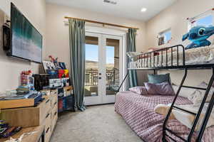 Bedroom with french doors, multiple windows, light carpet, and access to exterior