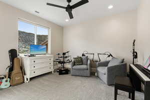 Living area featuring light colored carpet, a ceiling fan, and recessed lighting