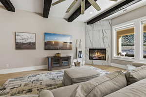 Living area with recessed lighting, a premium fireplace, light wood-style flooring, beamed ceiling, and ceiling fan