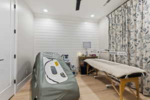 Rec room featuring light wood-type flooring, recessed lighting, wooden walls, and a ceiling fan