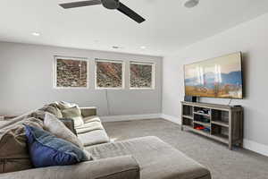 Carpeted living room with a ceiling fan and baseboards