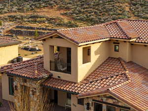 View of front of property featuring stucco siding, stone siding, and a balcony
