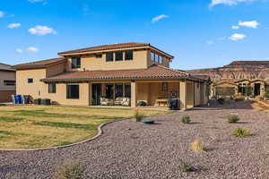 Back of property featuring a patio area, stucco siding, a tile roof, and a yard