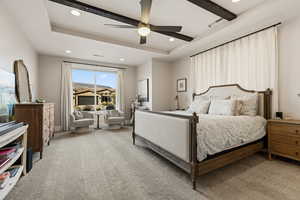 Bedroom with light colored carpet, a tray ceiling, a ceiling fan, and recessed lighting