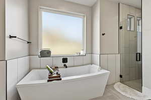 Full bath with a stall shower and a freestanding tub