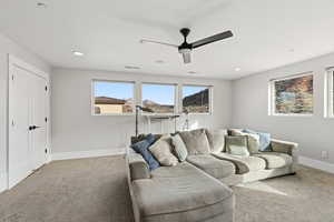 Carpeted living area featuring ceiling fan and recessed lighting