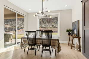 Dining space featuring light wood-style floors, hanging lights, and healthy amount of natural light
