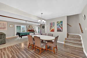 Dining space featuring light wood-style flooring, suspended lighting, a textured ceiling, and pool table