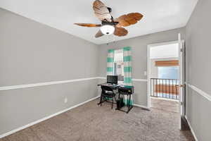 Carpeted office space featuring ceiling fan and baseboards