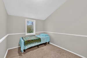 Bedroom with light colored carpet and a textured wall