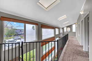 Corridor with lofted ceiling, a skylight, and carpet flooring