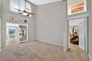 Spare room featuring a high ceiling, ceiling fan, and light colored carpet