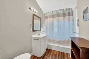 Full bath featuring vanity, dark wood finished floors, shower / tub combo, and lofted ceiling