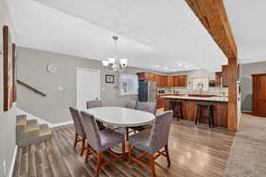 Dining space with suspended lighting, light wood-style floors, and a textured ceiling