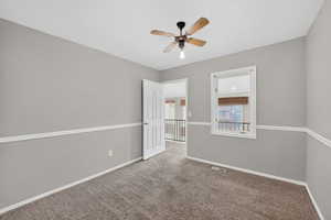 Carpeted empty room with baseboards and a ceiling fan