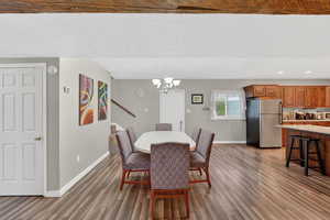 Dining space with suspended lighting and dark wood-style flooring