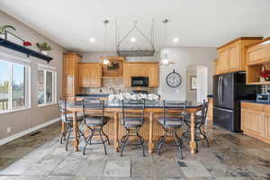 Kitchen with open shelves, arched walkways, dark countertops, and stone tile floors