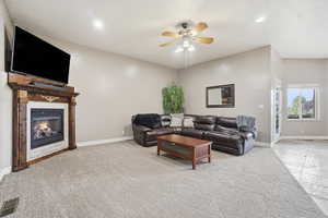 Living room with a glass covered fireplace, a ceiling fan, light colored carpet, and recessed lighting