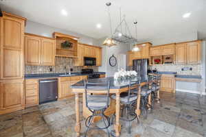 Kitchen with open shelves, black appliances, dark countertops, arched walkways, and stone tile floors