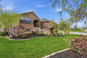 View of front of home featuring brick siding and a mature front yard
