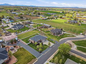 Aerial view of property showing fully fenced backyard and separate fully fenced horse pasture area and surrounding area with nearby suburban area and a mountainous background